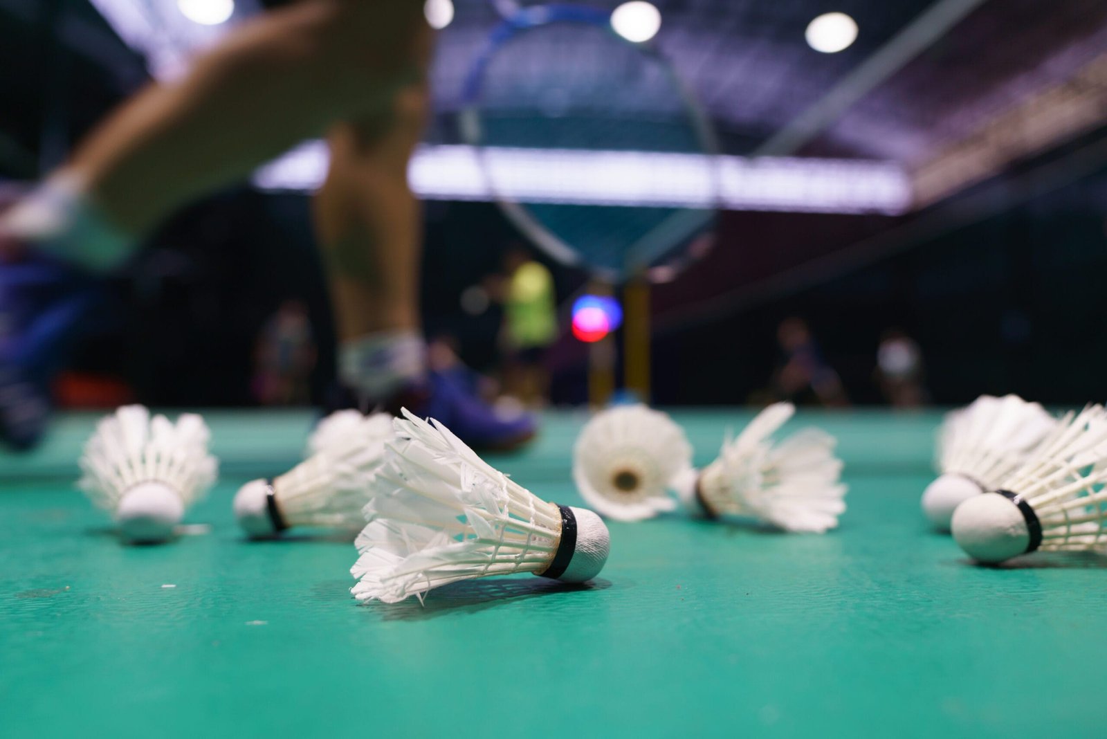 Scattered shuttlecocks on a badminton court during a casual game, highlighting the impact on foot comfort and the need for insoles for badminton shoes