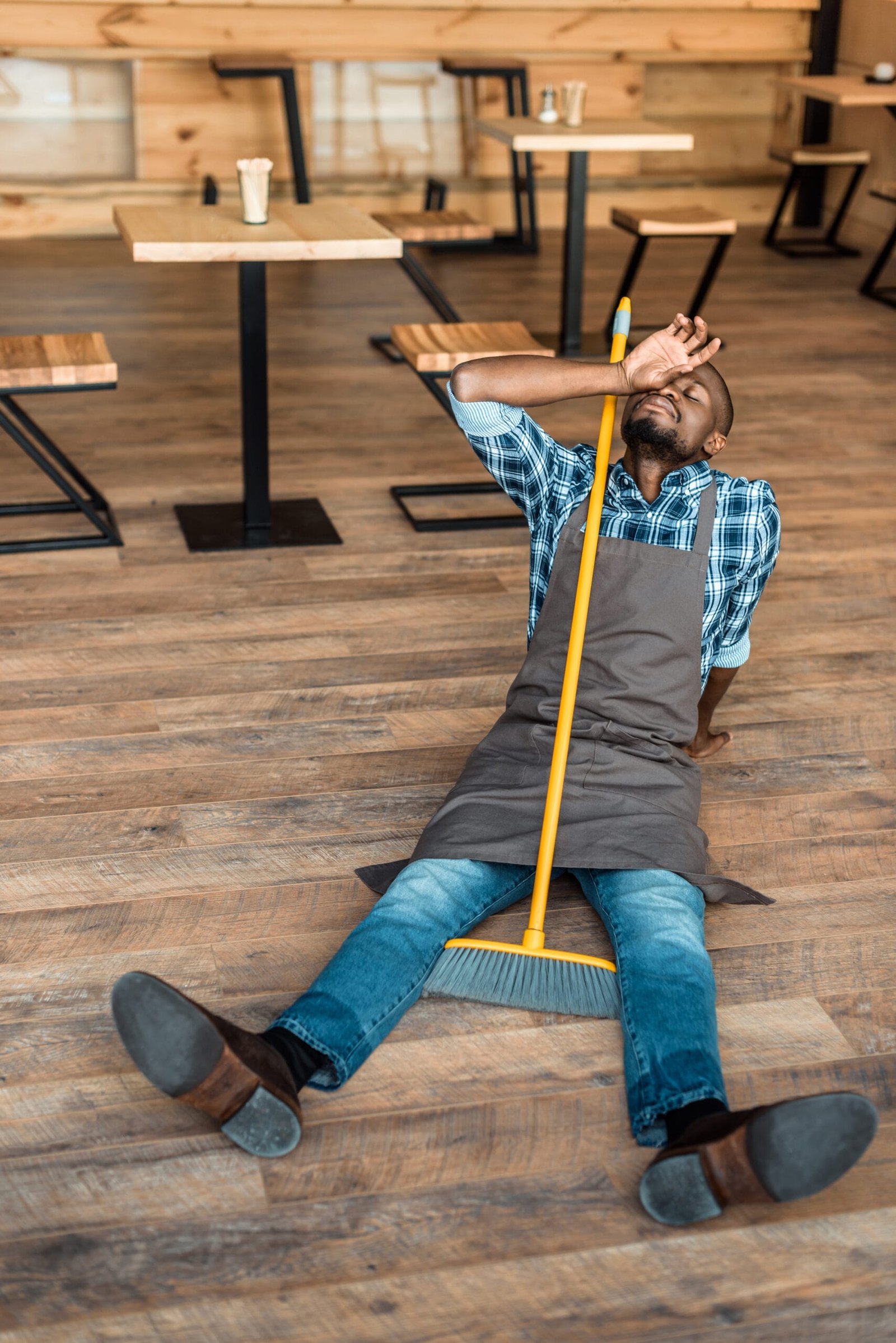 Tired barista resting on the floor after a long shift, showing the need for bounze insoles for standing work.