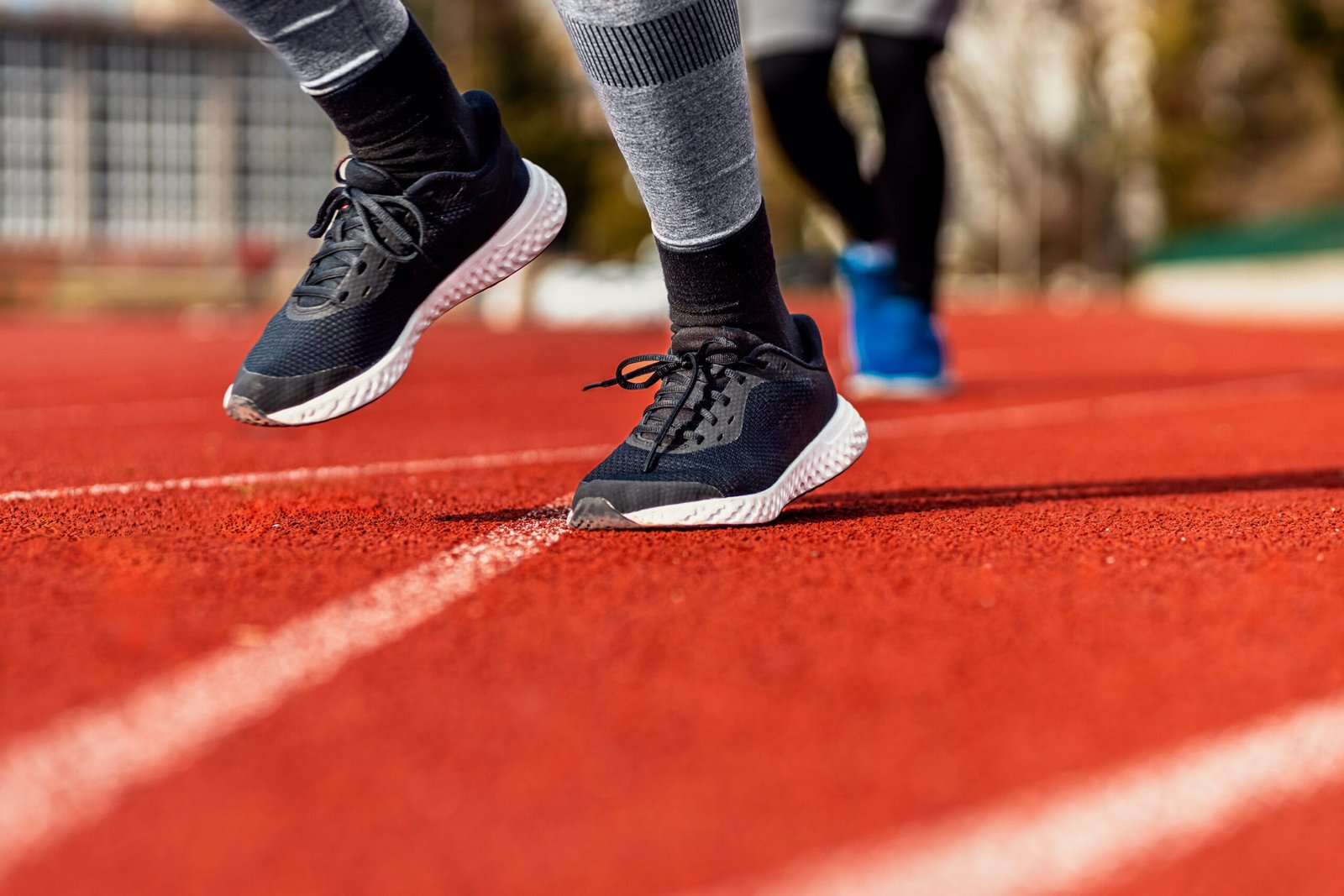Close-up of a runner’s feet running on a track, demonstrating the benefits of running with custom insoles for better support and comfort.
