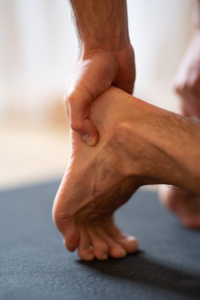 Man holding his heel due to sore feet after standing all day, showing foot pain and the need for relief